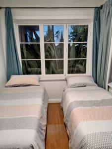 2 camas en una habitación con ventana en Little Gem - City Centre, en Hamilton