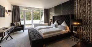 Schlafzimmer mit einem Bett, einem Schreibtisch und einem Fenster in der Unterkunft Hotel Luisenpark in Bad Bergzabern