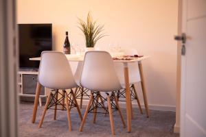 een tafel met drie witte stoelen en een tafel met wijnglazen bij Walnut Flats-F4, 2-Bedroom with Ensuite - Parking, Netflix, WIFI - Close to Oxford, Bicester & Blenheim Palace in Kidlington