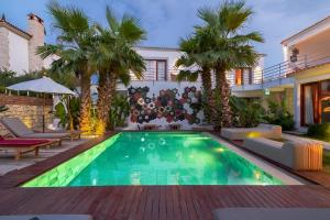 a pool in a backyard with palm trees and a house at 777 Alaçatı Adults only in Alacati