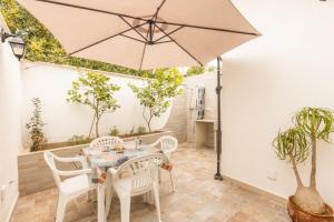 een patio met een tafel en stoelen en een parasol bij Giulio’s Apartment in Taviano