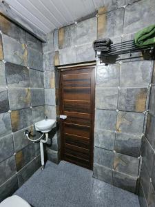 a bathroom with a toilet and a sink and a door at Wildways Mudumalai Homestay in Masinagudi