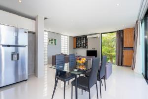 Una cocina y un comedor con una mesa de cristal y sillas. en Villa Natural Touch A3, en Kamala Beach