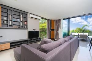 Una sala de estar con un sofá y un televisor de pantalla plana. en Villa Natural Touch A3, en Kamala Beach