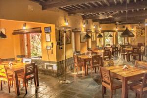a restaurant with wooden tables and chairs in a room at Prakriti Aalay - Riverside Mountain View Boutique Eco Resort in Dharamshala