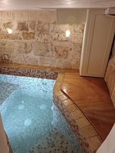 een zwembad in een kamer met een stenen muur bij Al Chiasso 12 in Monopoli