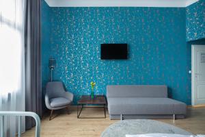 a living room with a couch and a tv on a blue wall at Hotel BELLEVUE am Kurfürstendamm in Berlin