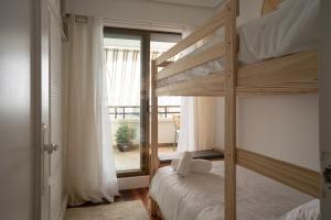 a bedroom with two bunk beds and a balcony at MENDILAUTA in Zarautz