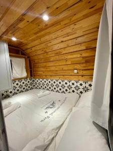 uma cama num quarto com uma parede de madeira em קסיופאה חוויה במדבר em Yeroẖam