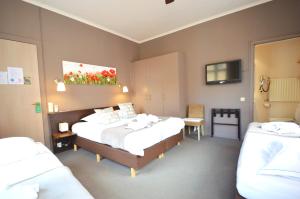 a hotel room with two beds and a television at Hotel Ambrosia in Ieper