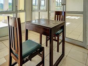 una mesa de madera y una silla junto a una mesa y una mesa en SPOT ON 92374 Penginapan Rusunawa, en Malang