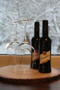 three wine bottles and glasses on a wooden tray at Waldpension Pfeiferhaus in Warmensteinach