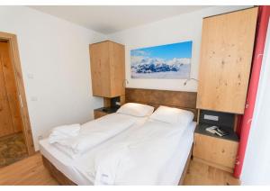 um quarto com uma cama branca e armários de madeira em Apartment am Sonnenhang Top 6 em Neukirchen am Grossvenediger