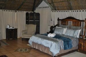 a bedroom with a large bed and a chair at Cashan BnB in Rustenburg