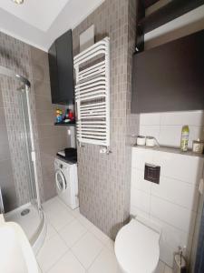 łazienka z toaletą i pralką w obiekcie Central Apartments Garnizon 928 & Parking w Gdańsku +35 zdjęć