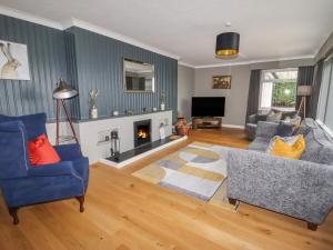 a living room with two blue chairs and a fireplace at Coedfan in Ruthin