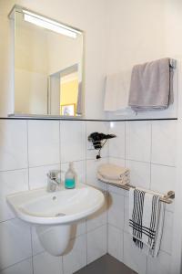 Baño blanco con lavabo y espejo en Gasthaus Herrig, en Meckel