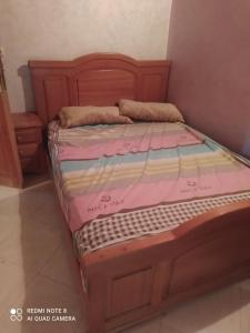 um quarto com uma cama com uma estrutura em madeira em N42 Residence Amine em Ifrane