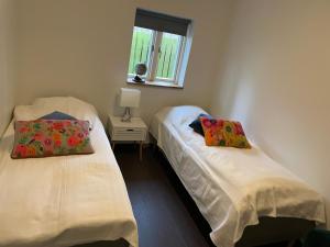 2 camas individuales en una habitación con ventana en Ledvogterhuset B&B en Faxe