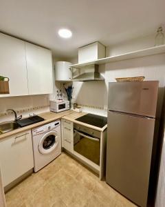 a kitchen with white cabinets and a washer and dryer at RentitSpain Puerta de la Ragua in Picena