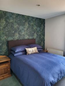 um quarto com uma cama com um edredão azul em The Garden Rooms at Tannery House em Bakewell