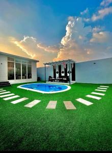 a house with a green lawn with a swimming pool at شاليهات قولدن GOLDEN محايل in Muhayil