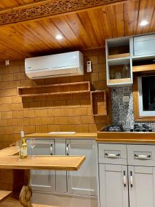a kitchen with white cabinets and a wooden wall at קסיופאה חוויה במדבר in Yeroẖam