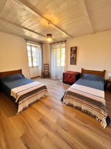 2 Betten in einem großen Zimmer mit Holzböden in der Unterkunft A Funtanella, maison de caractere situe entre montagne et mer in Tavera