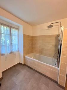 ein Bad mit einer Badewanne und einem Fenster in der Unterkunft A Funtanella, maison de caractere situe entre montagne et mer in Tavera