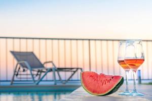 a glass of wine and a slice of watermelon on a table at Villa Panthea in Keratokampos
