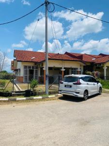 a white car parked in front of a house at LH Homestay Bandar Utama Gua Musang in Gua Musang