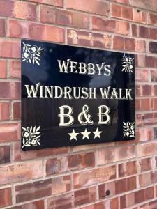 Un cartello su un muro di mattoni che leggeva "Swickedkritkritwalk bc" di Webbys Windrush Walk a Bourton on the Water