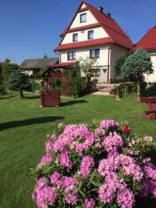 uma casa com flores cor-de-rosa em frente a um quintal em Agroturystyka Pod Dzwonnicą em Zubrzyca Górna