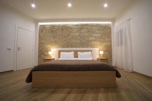a bedroom with a large bed and a brick wall at Boscò Suites in Carini