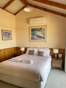 a bedroom with a large white bed with two lamps at Warby Cottage in Wangaratta