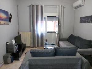 a living room with a couch and a tv at Airport's Close, Cozy Flat for 6 Persons in Markopoulo