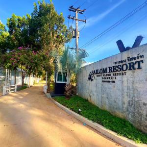 a wall with a sign on it next to a street at สายลม รีสอร์ท เขาใหญ่ in Pak Chong