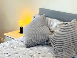 un letto con cuscini e una lampada su un tavolo di Webbys Windrush Walk a Bourton on the Water