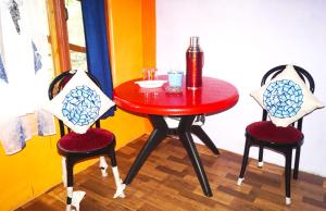 uma mesa com duas cadeiras e uma mesa vermelha com uma garrafa em Yumasham Homestay em Darjeeling