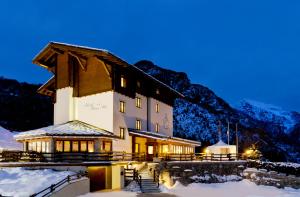 un edificio con techo en la nieve por la noche en Hotel Beau Site, en Brusson