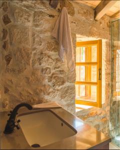 a bathroom with a sink and a stone wall at Roots Dhermi in Dhërmi