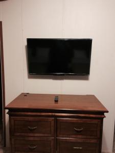 a flat screen tv on a wall above a wooden dresser at Oasis Lodge in Big Lake