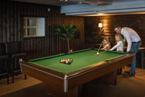 een man en twee kinderen spelen met een pooltafel bij Hotell Gyllene Hornet in Tällberg