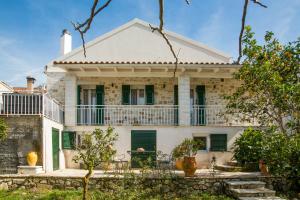 uma velha casa branca com persianas verdes em Vive Mar Paxos em Gaios