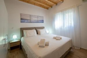 a bedroom with a large white bed with towels on it at Vive Mar Paxos in Gaios