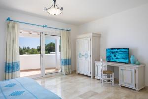 1 dormitorio con cama, TV y balcón en Nicolaus Club Quattro Lune Resort, en Cala Liberotto