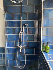 a blue tiled shower with a shower head in a bathroom at Stay Northside - Log Burner, Luxury Countryside Cottage County Durham 