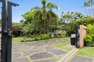 un jardín con palmeras y una pasarela de piedra en Lanikai Ohana Hale, en Kailua