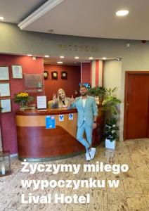 two people standing at a reception desk in a hotel at Hotel Lival in Gdańsk