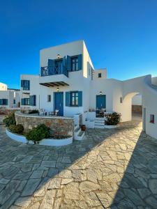 a large white house with blue doors and a patio at Horizon Hotel in Chora Folegandros